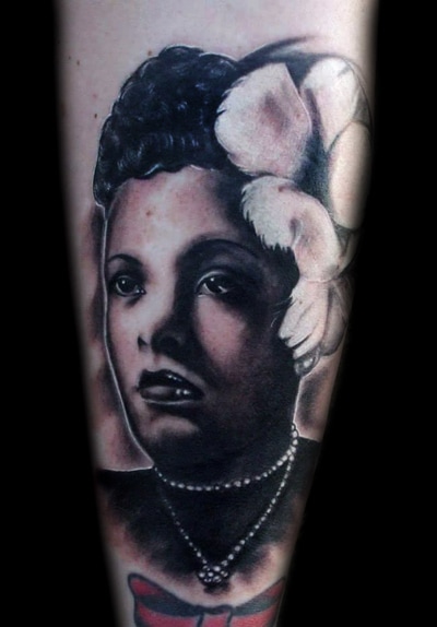 Black and grey realism tattoo of a woman's face with feathers and pearls.