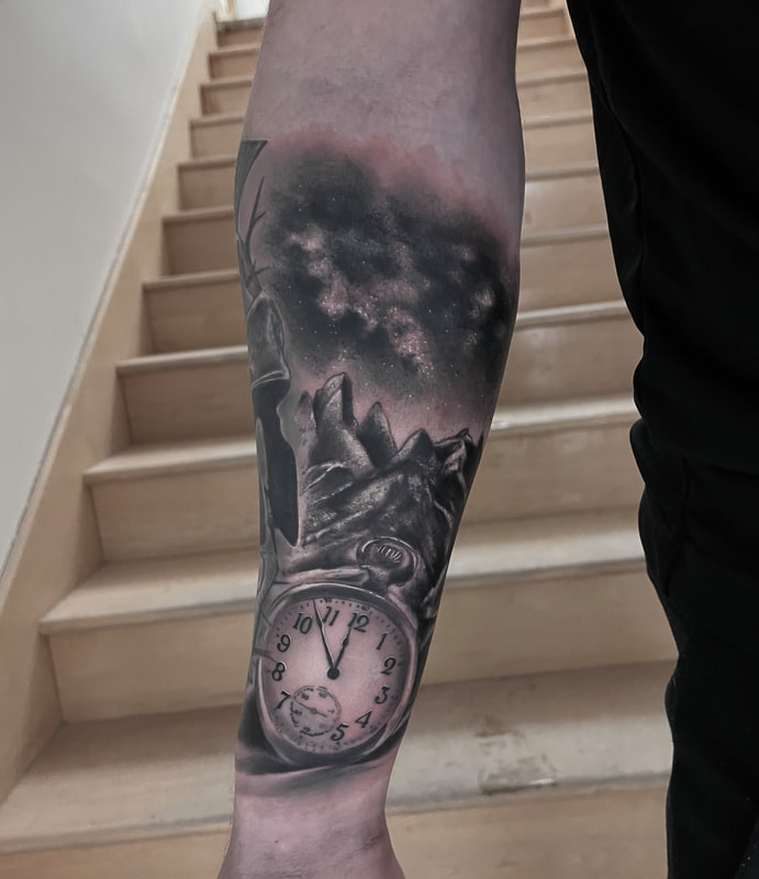 Realistic black and grey tattoo of a clock and mountains on a forearm.