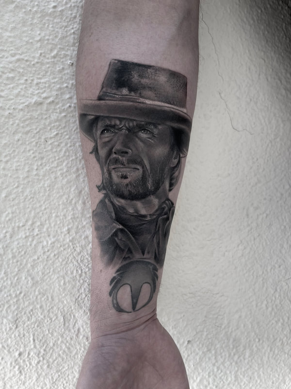 Black and grey realistic tattoo of Clint Eastwood on a forearm.