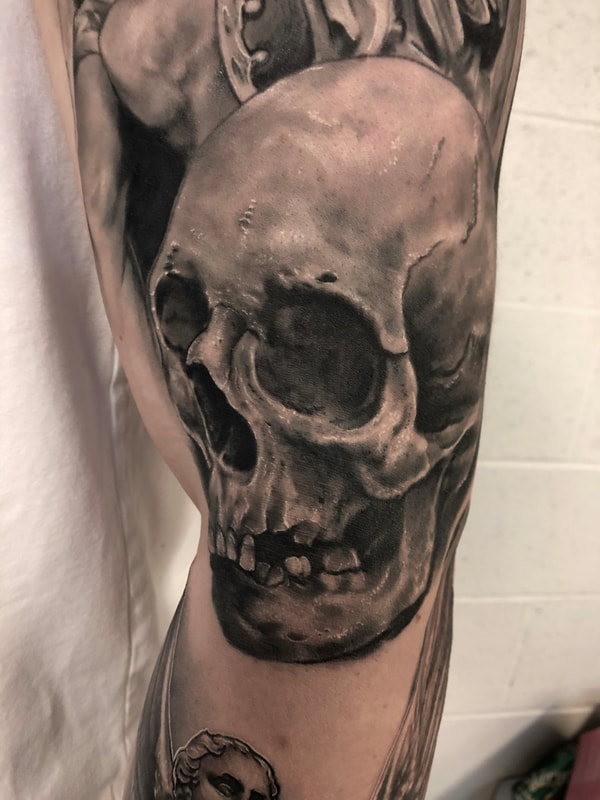 Realistic black and gray skull tattoo on a man's arm.
