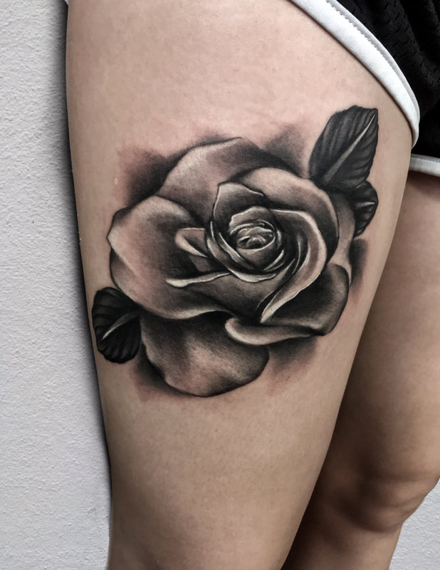 Realistic black and gray rose tattoo on a thigh.