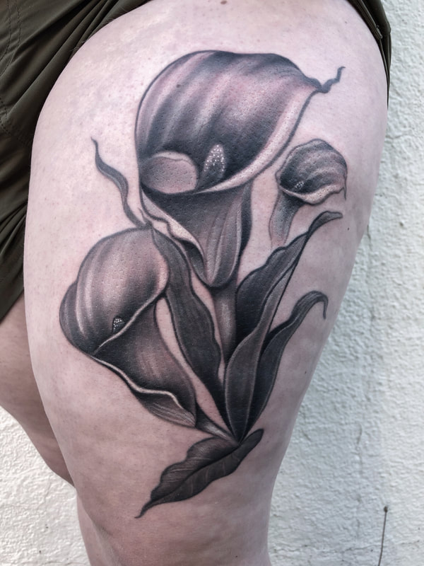 Realistic black and gray calla lilies thigh tattoo.
