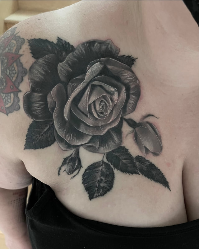 Black and grey realistic rose on a woman's chest.