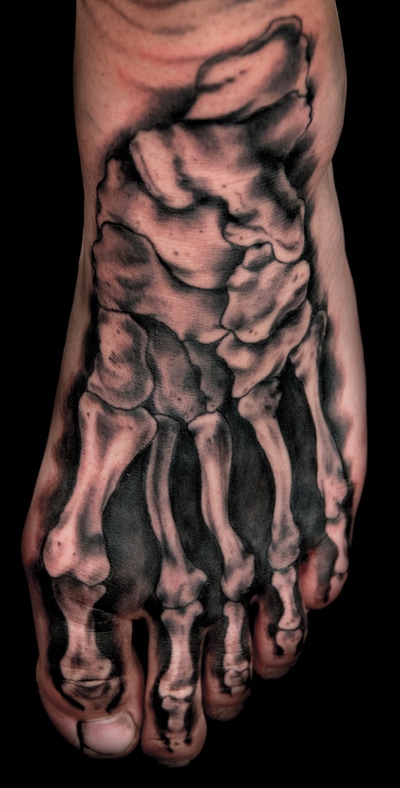 Realistic black and gray tattoo of skeletal structure of foot bones on a foot.