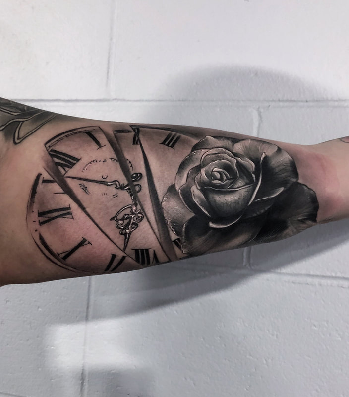 Realistic black and gray clock and rose tattoo on inner bicep.