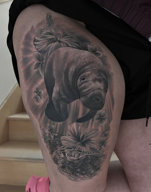 Black and grey realistic tattoo of a manatee swimming under water with flowers and coral reef on a thigh.