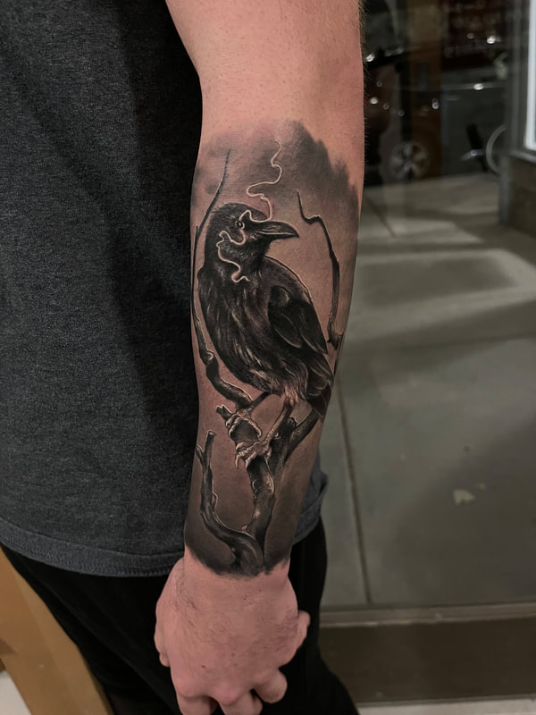 Black and grey realistic tattoo of a crow with a lightning bolt through its eye on a forearm.