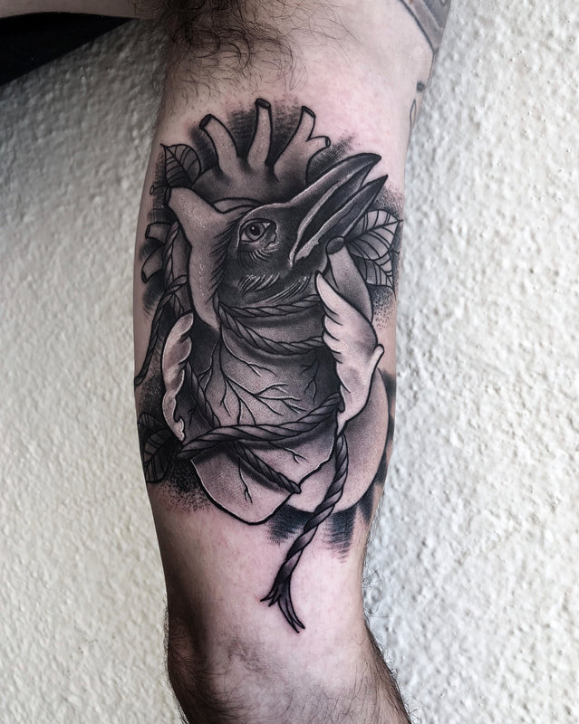 Black and gray tattoo of an anatomical heart with a raven in the inner bicep.