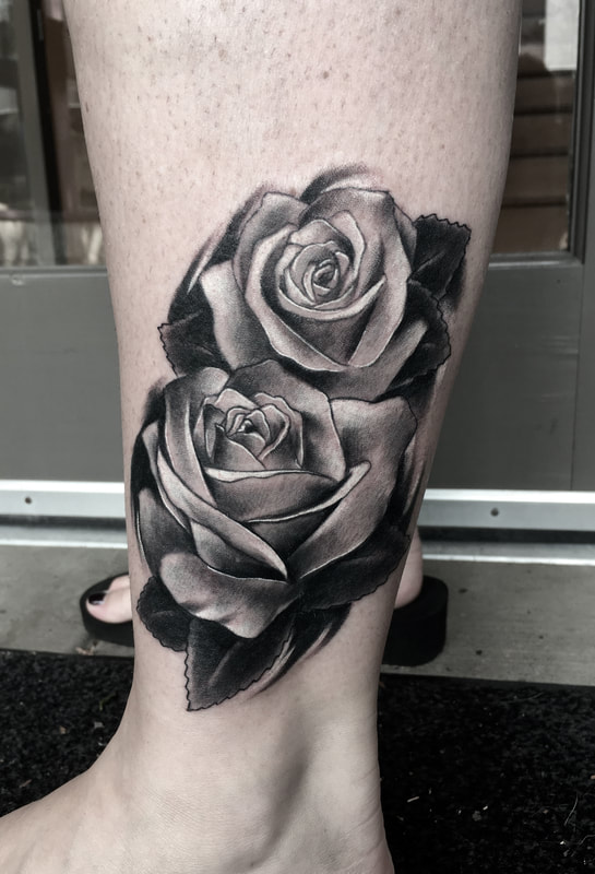 Black and gray realism tattoo of roses on an ankle.