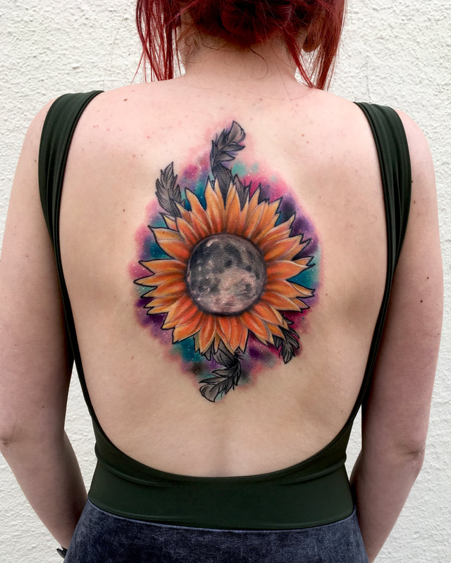 Color realism tattoo of a sunflower with a moon center and pink, blue, and purple galactic background on a woman's spine.