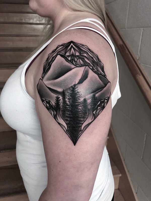 Black and gray mandala the mountains and trees on shoulder.