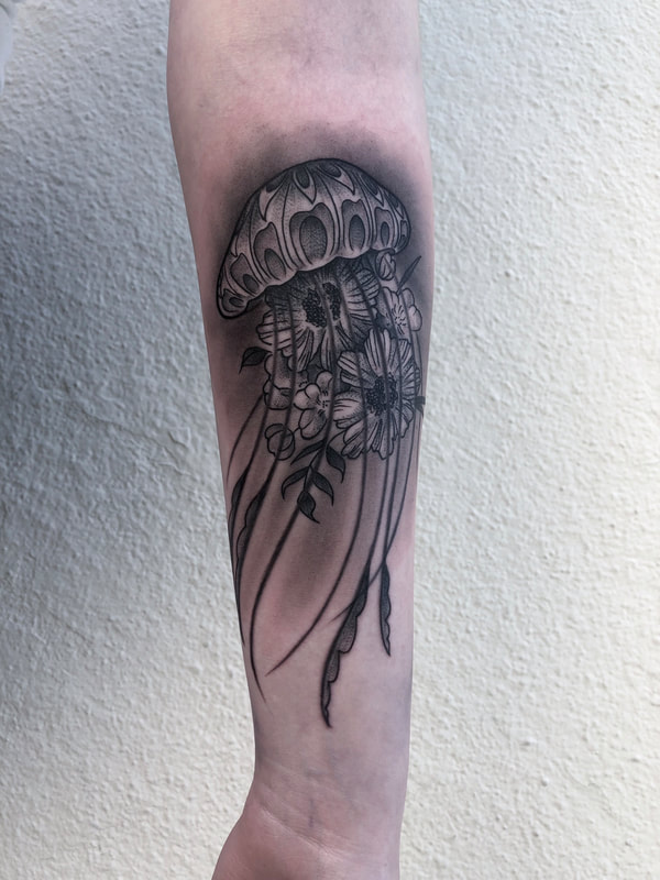 Black and gray realism tattoo of jellyfish with flowers on a forearm.