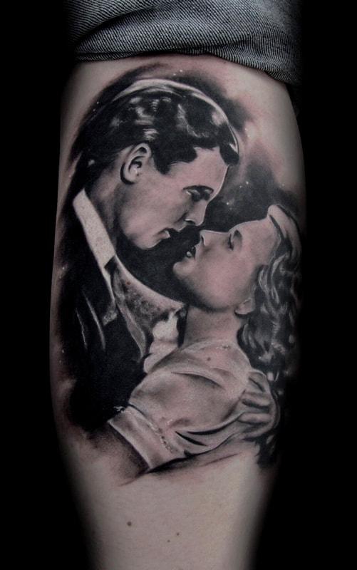 Black and grey realistic tattoo of the movie, It’s a Wonderful Life, with a man and woman facing one another about to kiss.