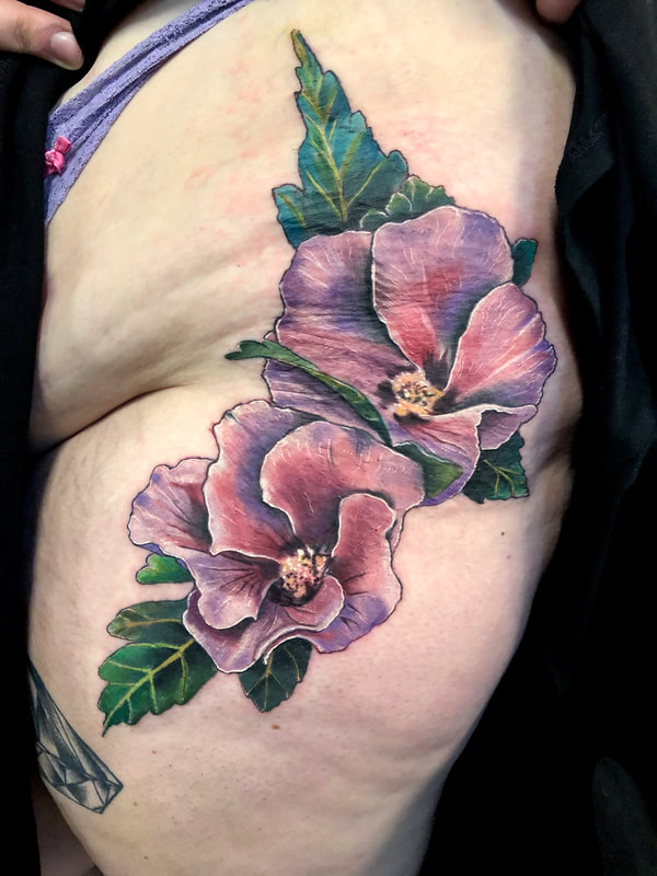 Realistic purple hibiscus tattoo on a woman's upper thigh and hip.