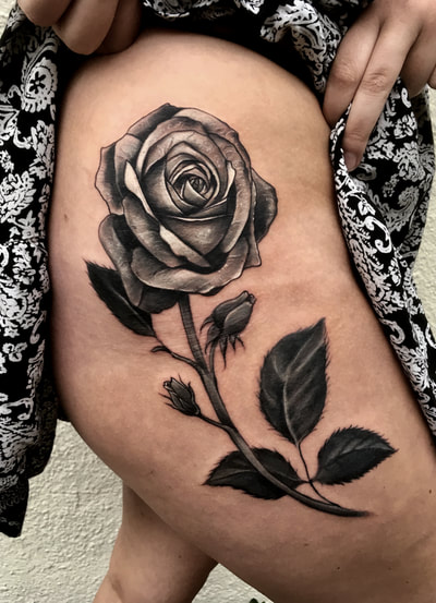 Realistic black and gray rose thigh piece tattoo.
